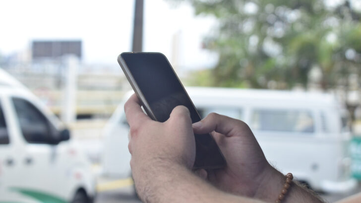 Mão segura celular em ambiente externo