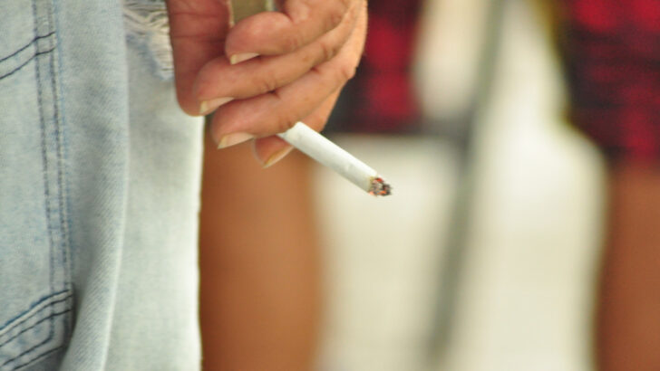 Mão de mulher segura um cigarro aceso