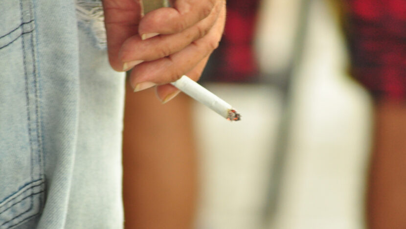 Mão de mulher segura um cigarro aceso