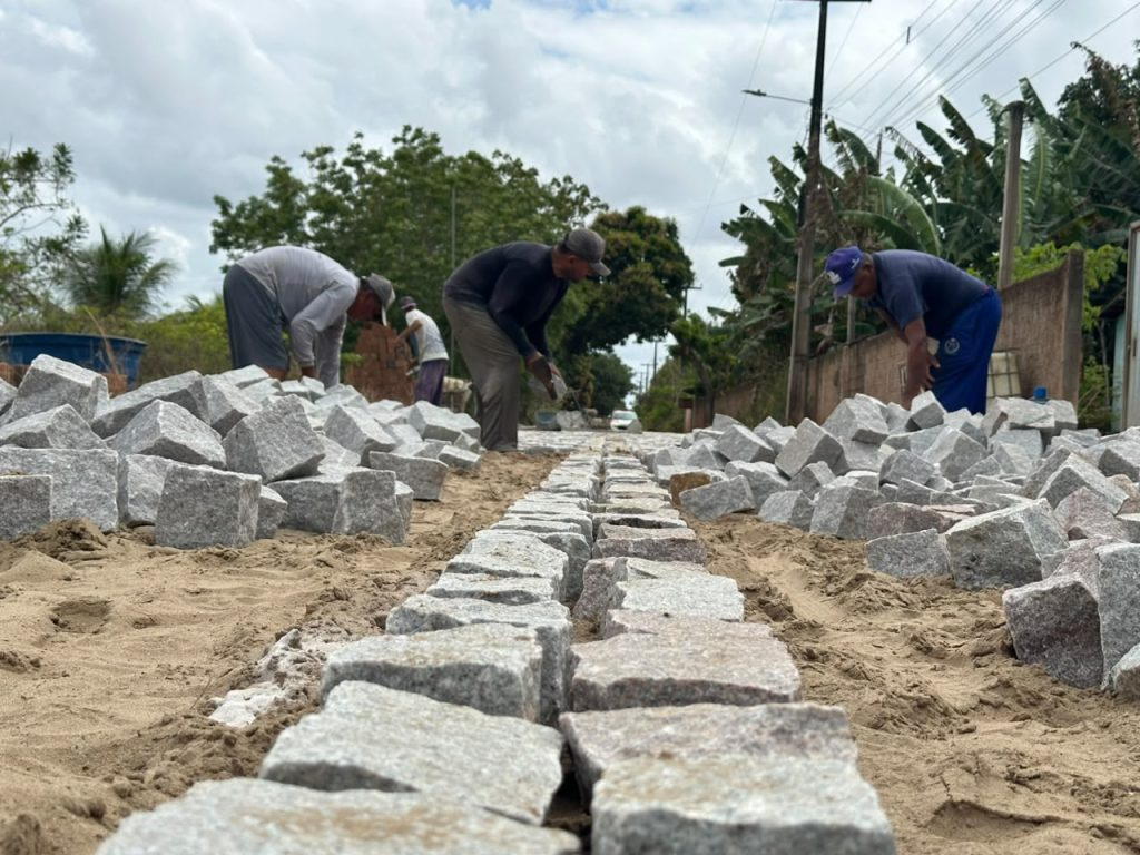 Trabalhadores assentam paralelepípedos durante obra de pavimentação em Japecanga, em Macaíba