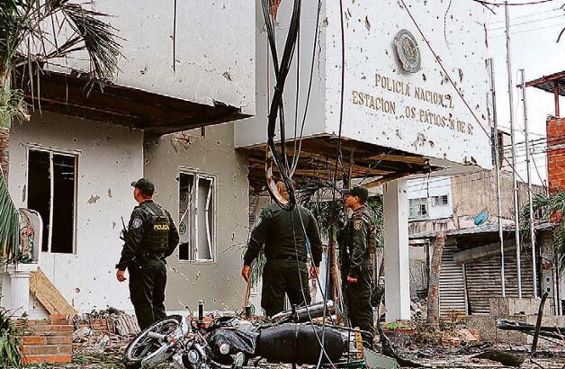 Policiais colombianos observam prédio danificado após explosão de carro-bomba