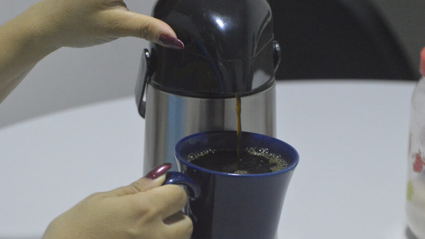 Café sendo servido de uma garrafa térmica em uma caneca