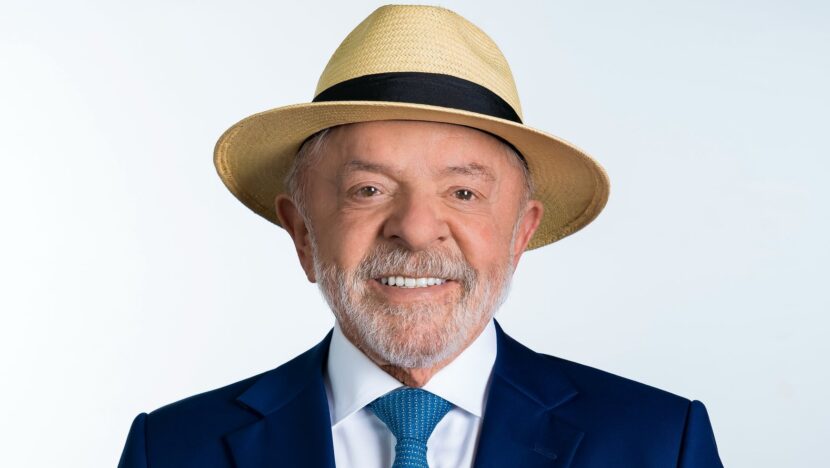 Retrato de estúdio do presidente Luiz Inácio Lula da Silva, de chapéu de palha, terno azul-marinho e gravata azul, sobre fundo branco