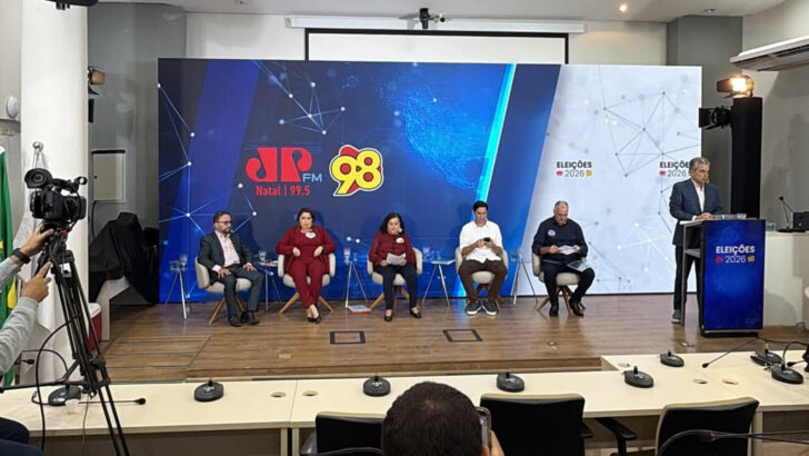 Cinco candidatos ao Senado sentados no palco durante debate no auditório do Crea-RN