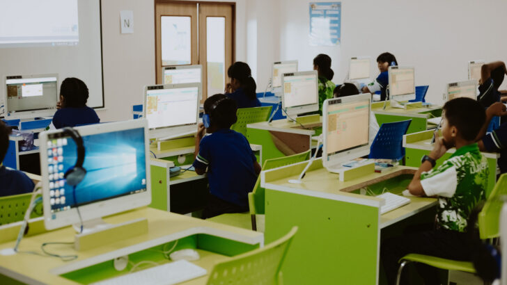 Estudantes uniformizados usam computadores em laboratório de informática de uma escola