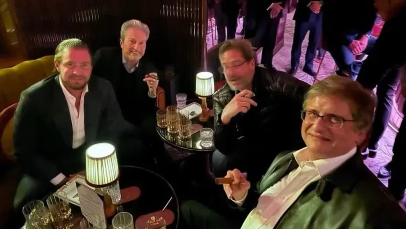 Paulo Gonet, Daniel Vorcaro e outras duas pessoas sentados a mesas em encontro em Londres, com charutos nas mãos