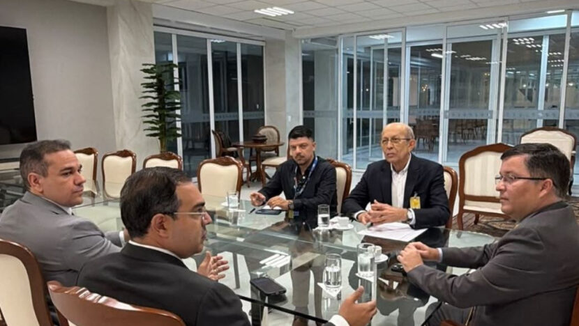Reunião em sala institucional com participantes sentados à mesa