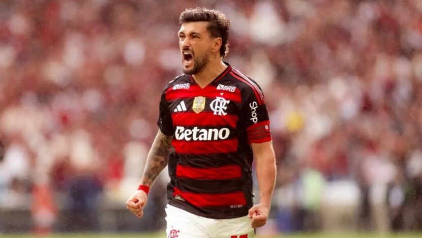 Jogador de futebol com uniforme rubro-negro comemora durante partida em estádio