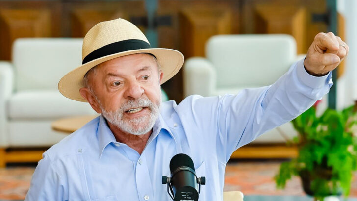 Presidente Lula, de chapéu de palha, gesticula diante de um microfone durante evento