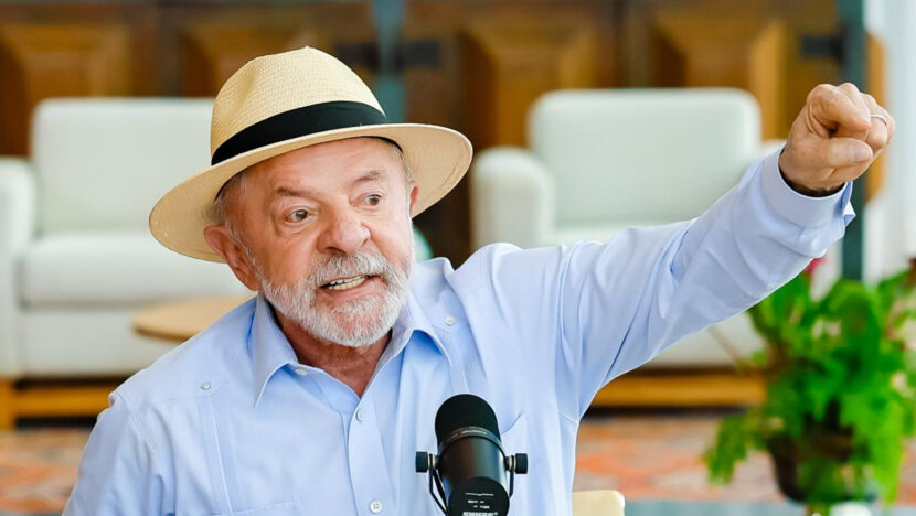 Presidente Lula, de chapéu de palha, gesticula diante de um microfone durante evento