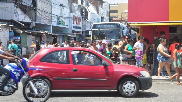 Pedestres, veículos e ônibus circulam em via comercial do bairro Alecrim, em Natal