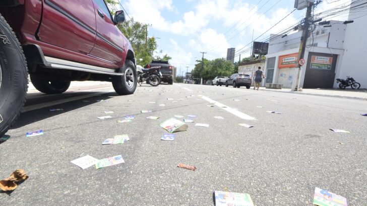 Santinhos eleitorais espalhados pelo asfalto de uma rua