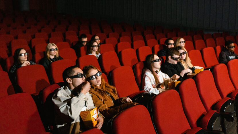 Plateia assiste a filme em sala de cinema com poltronas vermelhas