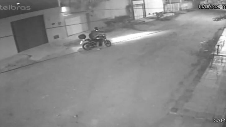 Imagem noturna de câmera de segurança mostra uma pessoa em uma motocicleta circulando por uma rua