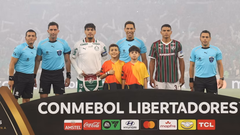 Jogadores de Palmeiras e Fluminense, árbitros e duas crianças posam atrás de placa da Libertadores no Maracanã