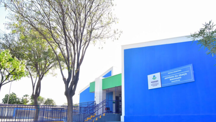 Fachada azul e verde da escola, com rampa e corrimãos na entrada