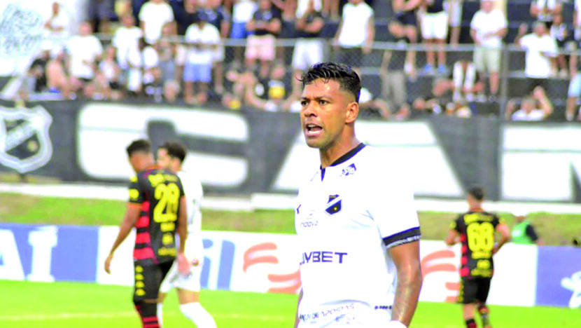 Wallyson, com uniforme branco do ABC, em campo diante de adversários