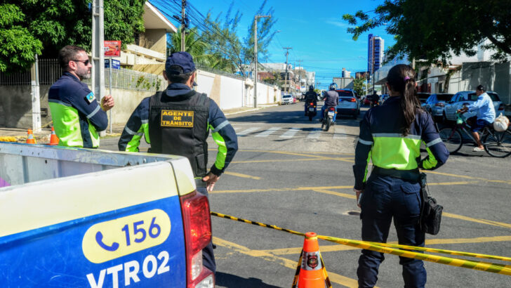 Agentes de trânsito ao lado de viatura e cones em uma rua de Mossoró
