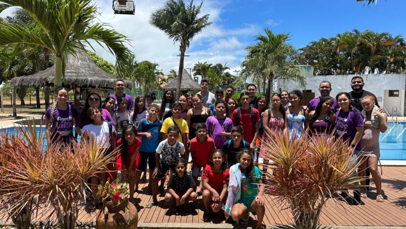 Grupo de crianças e adultos reunido ao lado de uma piscina na Fazenda Real III