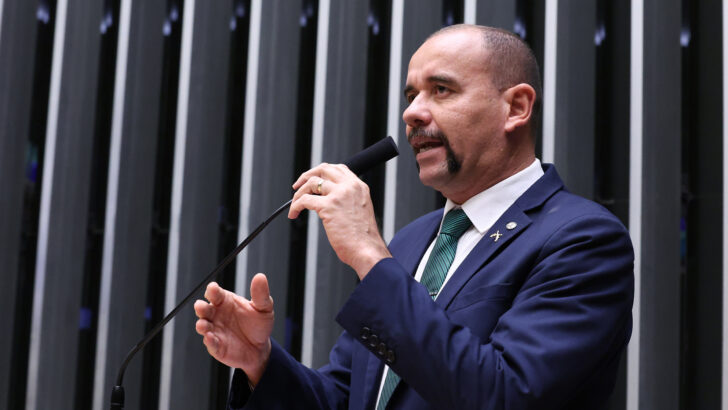 Deputado federal Sargento Gonçalves, de terno azul e gravata verde, discursa ao microfone em um plenário