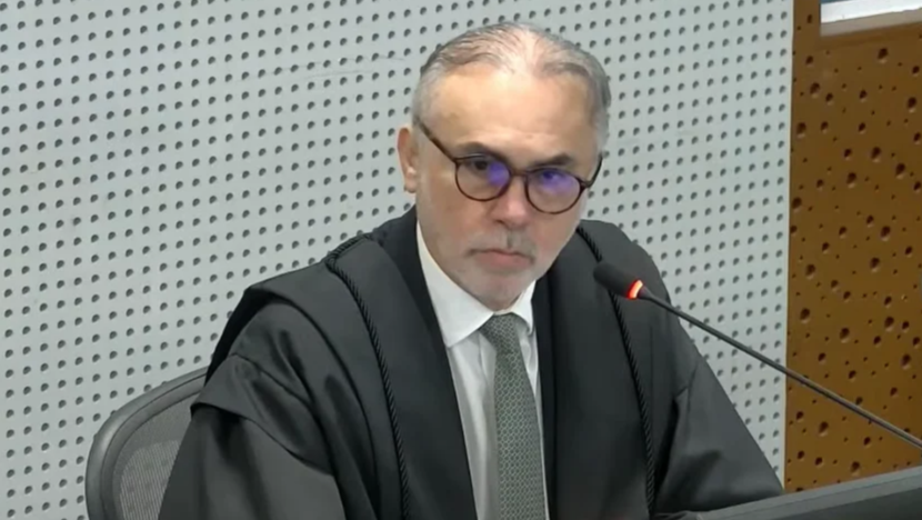 Desembargador Glauber Rêgo, de óculos e terno escuro, sentado diante de um microfone.