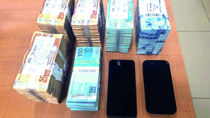 Notas de dinheiro e dois celulares apreendidos pela Polícia Federal