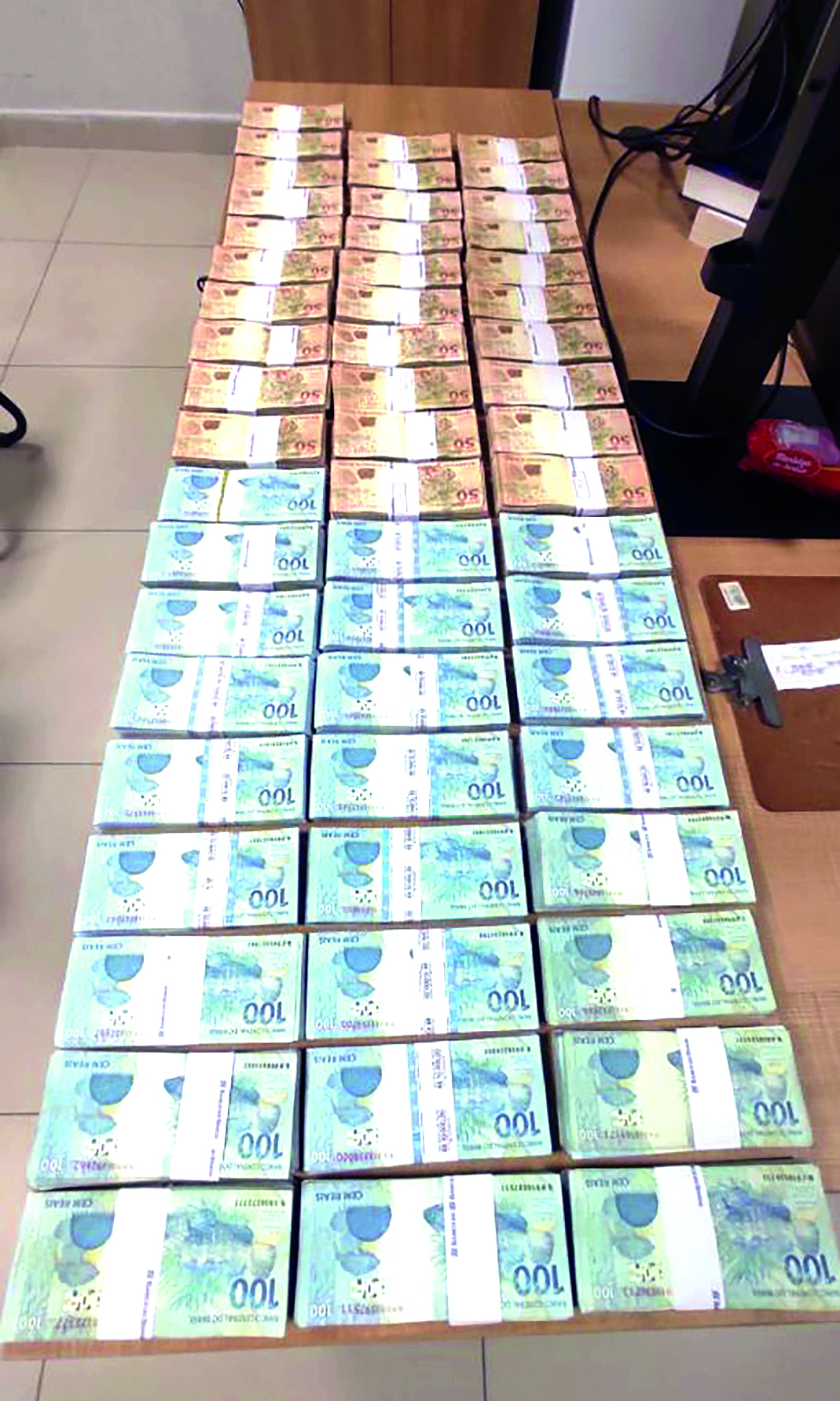 Cédulas de dinheiro apreendidas pela Polícia Federal dispostas em uma mesa