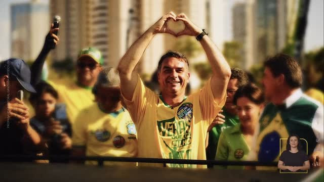 Flávio Bolsonaro faz um coração com as mãos diante de apoiadores