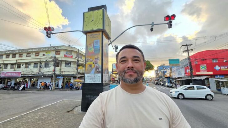Matheus Feitosa posa no Alecrim, diante do relógio e de estabelecimentos comerciais