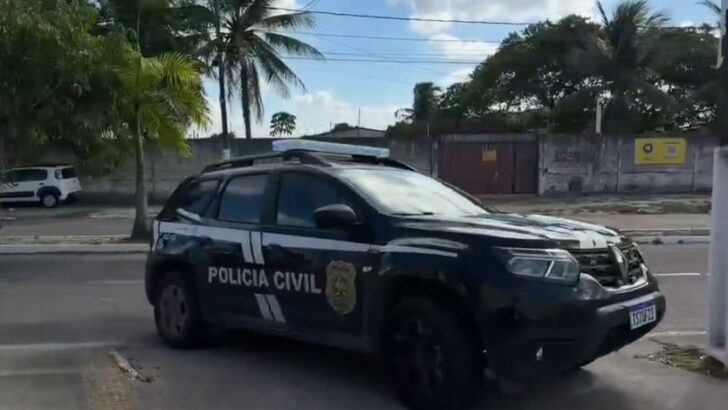 Viatura preta da Polícia Civil estacionada junto a uma calçada, com casas e palmeiras ao fundo