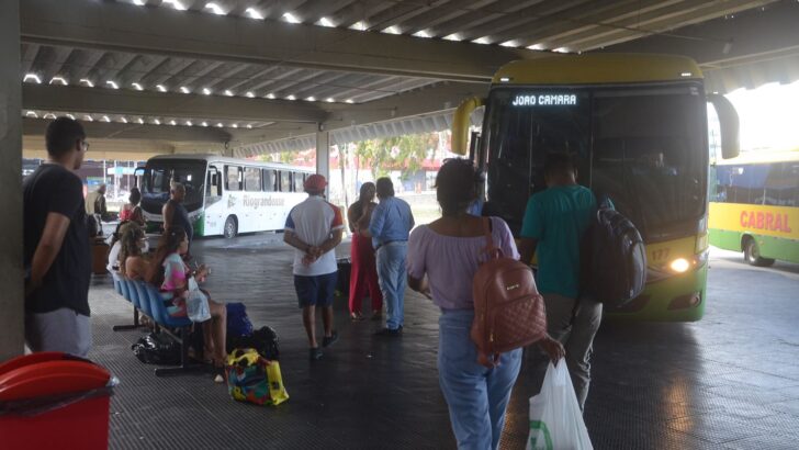 Passageiros aguardam junto a ônibus nas plataformas de um terminal rodoviário