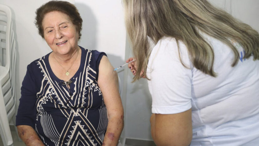 Profissional de saúde aplica vacina em uma mulher