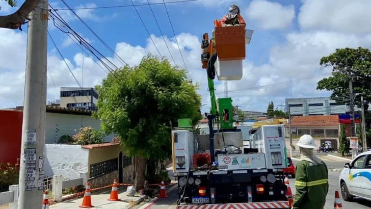 Trabalhadores realizam manutenção na rede elétrica com auxílio de caminhão e plataforma elevada