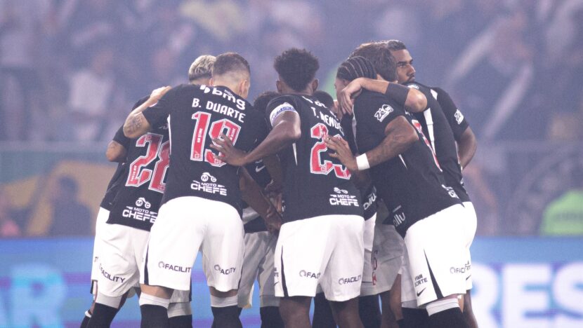 Jogadores do Vasco, com camisas pretas e calções brancos, se abraçam no gramado do Maracanã