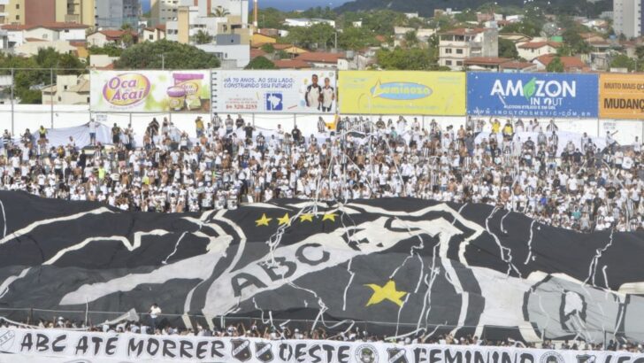 Torcida do ABC nas arquibancadas exibe bandeiras e faixa do clube