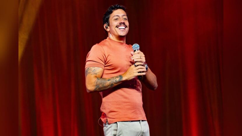 Renato Albani sorri e segura um microfone durante apresentação de humor