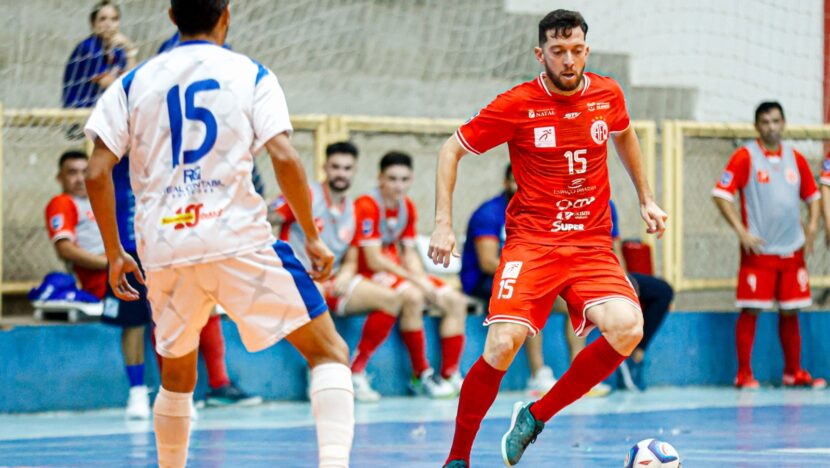 Jogador do América-RN conduz a bola diante de atleta do Cruzeiro de Assú em partida de futsal