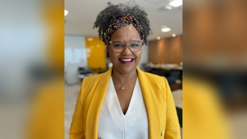 Superintendente Cristiane Maria, do Banco do Brasil, posa sorrindo com blazer amarelo