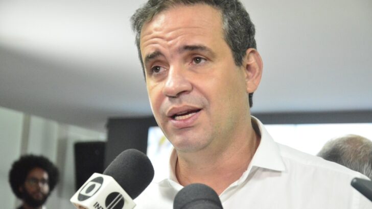 Cadu de Lula, de camisa clara, fala a jornalistas diante de microfones