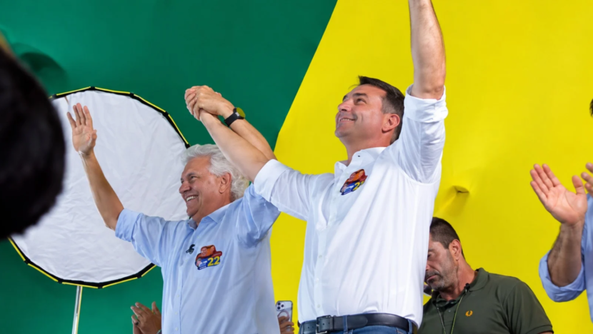 Ronaldo Caiado e Flávio Bolsonaro erguem os braços durante ato político