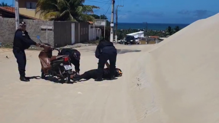 Agentes atendem motociclista caída ao lado de uma moto em trecho de rodovia coberto por areia