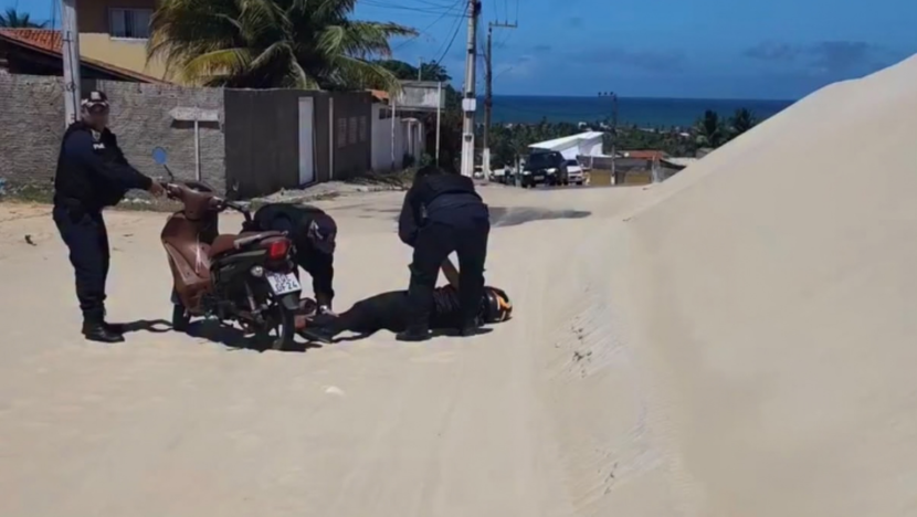 Agentes atendem motociclista caída ao lado de uma moto em trecho de rodovia coberto por areia