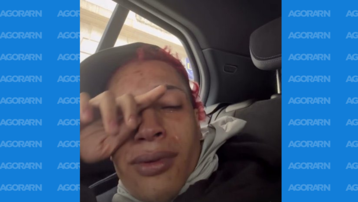 Pessoa de cabelos avermelhados, com os olhos fechados e a mão sobre o rosto, sentada no banco traseiro de um carro
