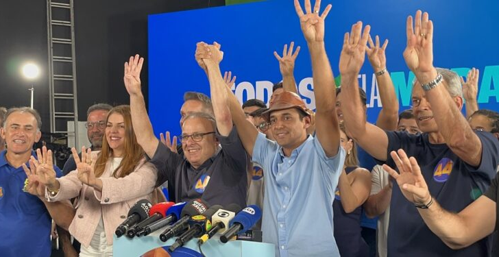 Allyson Bezerra, Paulinho Freire, Nina Souza e aliados erguem as mãos diante de microfones durante coletiva de imprensa