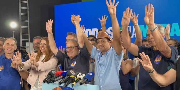 Allyson Bezerra, Paulinho Freire, Nina Souza e aliados erguem as mãos diante de microfones durante coletiva de imprensa