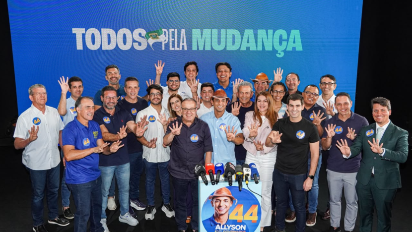 Paulinho Freire, Allyson Bezerra, Nina Souza e aliados posam atrás de microfones, fazendo o gesto do número quatro diante de painel azul com a frase Todos pela mudança