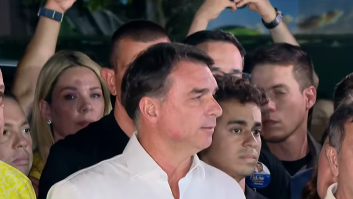 Flávio Bolsonaro, de camisa branca, fala cercado por apoiadores em Brasília