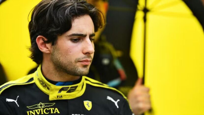 O piloto Rafael Câmara, de macacão preto e amarelo com o emblema da Fórmula 2 e o escudo da Ferrari, fotografado de perto nos boxes