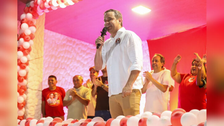 Cadu de Lula fala ao microfone em evento com apoiadores