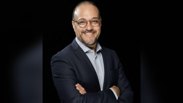 Márcio Coimbra, de óculos e terno, com os braços cruzados